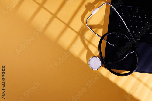 Digital health concept with a stethoscope on a laptop computer and a yellow background for medical insurance and pharmacy business.