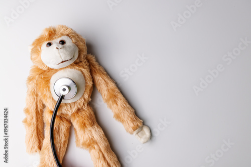 Obraz na plátně Pediatric healthcare concept with a plush monkey and stethoscope on a white background for medical clinic and child wellness ads