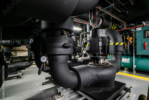 Industrial HVAC machinery with pumps and insulated piping in mechanical room