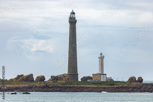 View of the Ile Vierge lighthouse and its smaller companion on a rocky islet under a cloudy sky in Plouguerneau, Bretagne, France.