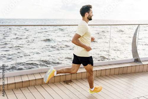 Fitness focused man running on a modern cruise ship deck beside the sea under blue sky