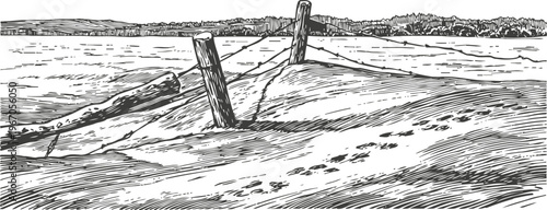 Wooden fence posts on sandy beach with footprints and distant shoreline horizon