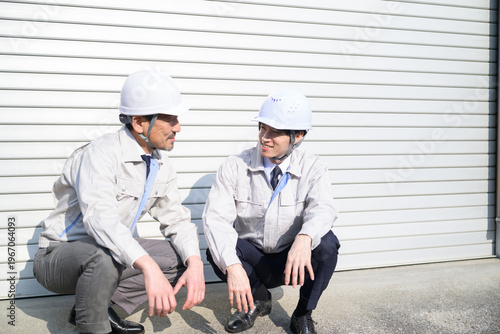 Canvastavla シャッターの前で座って話をする作業服の日本人男性