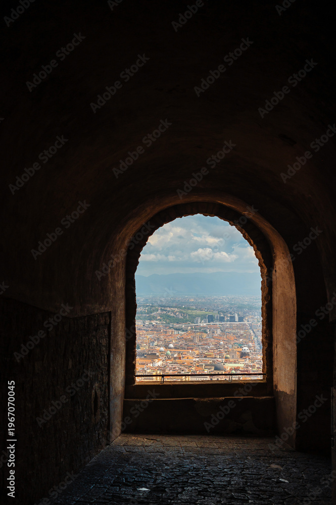 Fototapeta premium View of Naples cityscape through an ancient arched window from a historic building