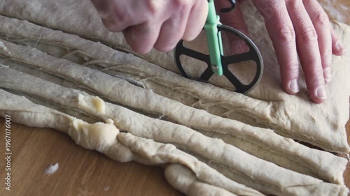 Soft rolled dough being cut with a pastry wheel, preparing for layered pastries and sweet buns.