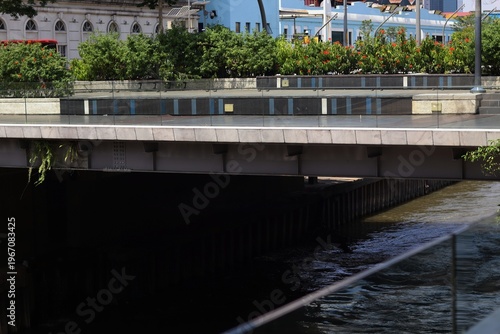 Photography Kuala Lumpur,Malaysia 23rd June 2023 Modern concrete pedestrian bridge stretching over a calm urban riverway with greenery along the banks in downtown Kuala Lumpur, Malaysia