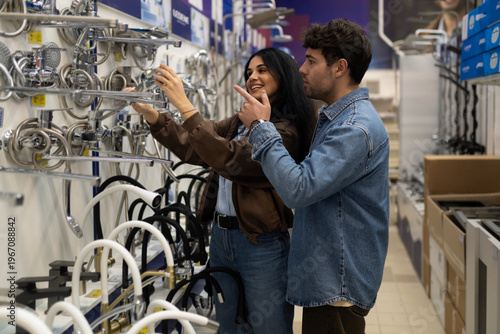 Young couple selecting plumbing fixtures at a hardware store for renovation
