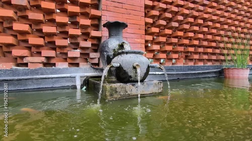 A decorative fountain in a mossy fish pond