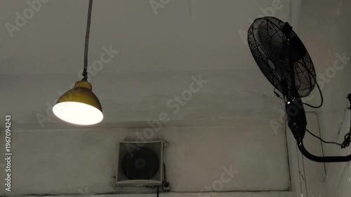 A hanging lamp in a room swaying due to the wind from the fan