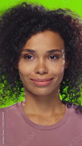 Portrait of young African American woman with curly hair displaying various facial expressions including smile and closed eyes on green background for emotion and mood.