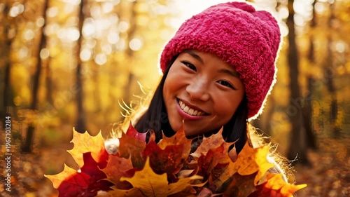 Young Asian Girl Smiling Happily Holding Autumn Leaves in a Forest During Fall