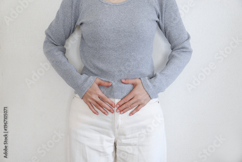 Foto タイトル 腹痛で腹部を押さえる女性
