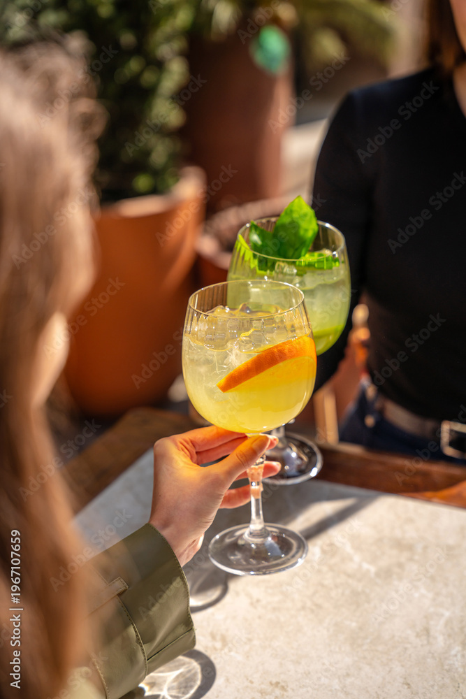 Obraz premium Friends toasting fresh citrus cocktails in warm sunlight