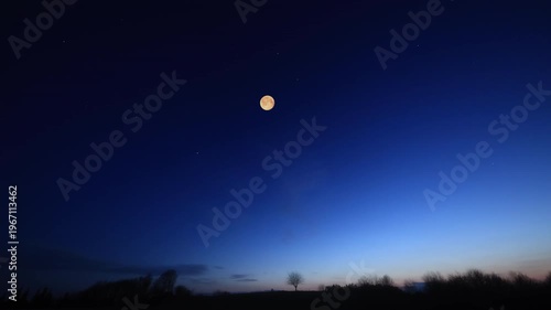 Full Moon, stars and planets above landscape silhouettes.