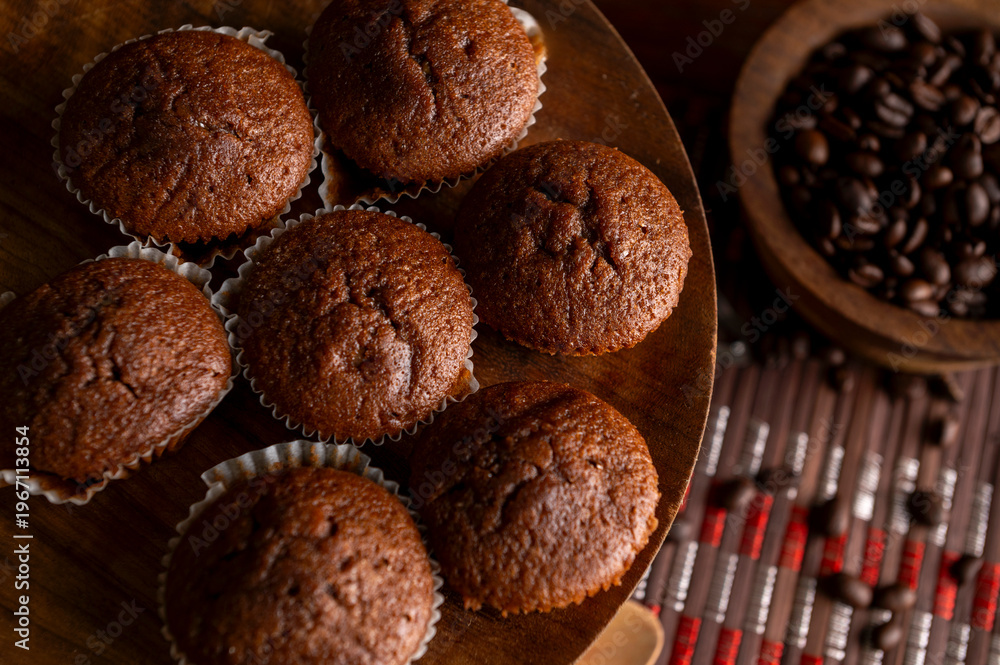 Fototapeta premium Homemade chocolate and cocoa muffins with coffee baked on a wooden board, traditional sweet chocolate bar pastry 
