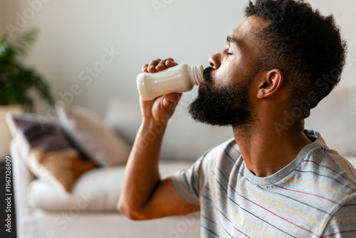 Young black man enjoying a probiotic drink for a healthy snack at home