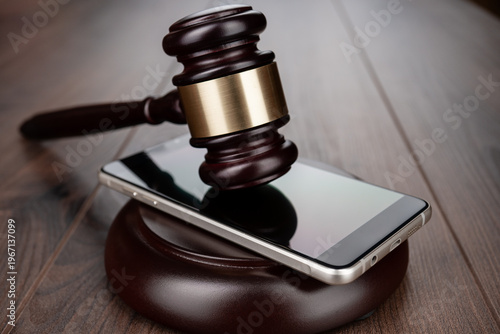 Wooden gavel on smartphone placed on round base. Concepts of court case in technology space and regulation.