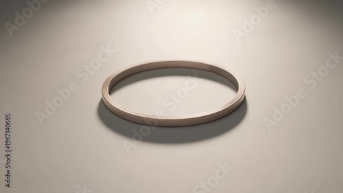 A 3D rendering of a metallic ring lies on a flat surface in a spotlight.