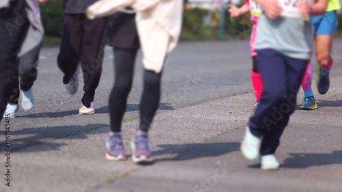 Footage of children and adult runners moving along a road, capturing natural motion and a lively sports atmosphere.