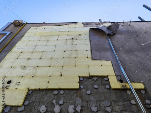 Low angle view of building renovation with insulation panels attached to exterior wall under clear blue sky background