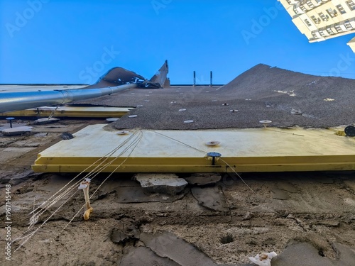 Building exterior under renovation with yellow insulation boards attached to damaged wall surface viewed from ground perspective