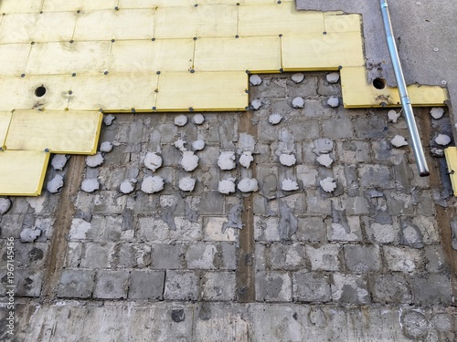 Close view of building facade with removed insulation panels exposing damaged wall surface during exterior renovation process