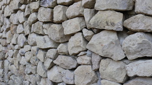 A stone wall of a fortress or fort, constructed from large gray cobblestones and viewed at an angle in receding perspective; stone and rock material found in ancient structures.