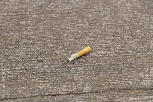 Photos Close up and top view of the finished cigarette butts thrown on concrete floor of the pavement in urban city shows bad habit in environment pollution and risk danger for people health