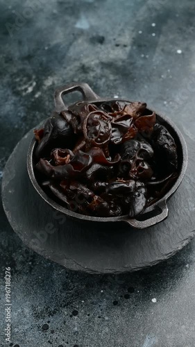 Cooking with black fungus in a metal pan on a dark surface