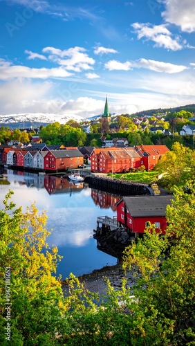 Vertical panorama colorful buildings line a blue river under a bright, cloudy sky