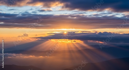 Sunset Over Mountain Range with Dramatic Cloudscape and Sun Rays in Vibrant Warm Colors