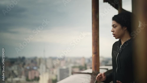 Young Black woman looking at city from a rooftop, facing her fear of heights