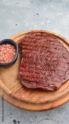 Grilling steak on wooden board with salt in a simple kitchen setup