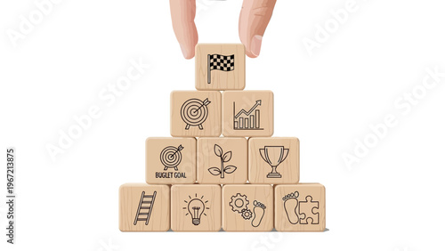 A hand placing a checkered flag on top of a pyramid of wooden blocks with various business and goal-oriented icons