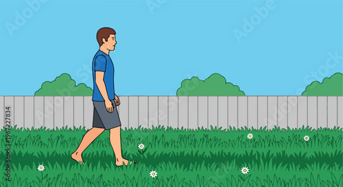 A barefoot man wearing a blue shirt and grey shorts walks across a green lawn