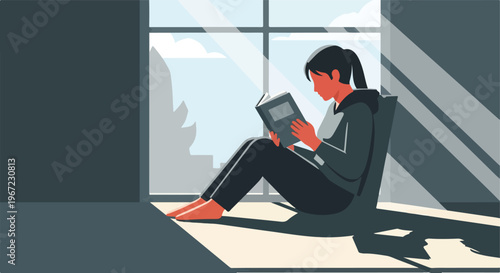 A young person sits near a large window reading a book in quiet afternoon light