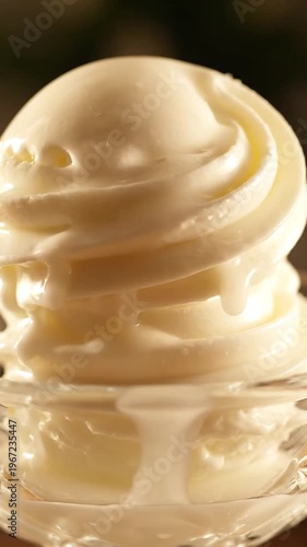 Close-up of creamy vanilla soft serve ice cream being scooped into a glass bowl on a dark background, dessert