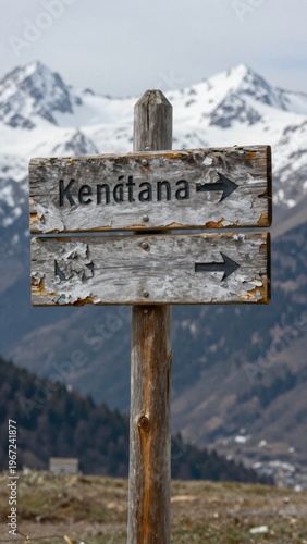 Weathered Wooden Direction Sign Post Indicating Trail to Kenjana Surrounded by Snowy Mountains
