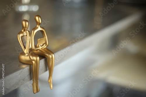 Tableau sur toile Modern golden abstract thinker statues sitting on a marble ledge, symbolic minimalist figures representing contemplation, philosophy, and home decor