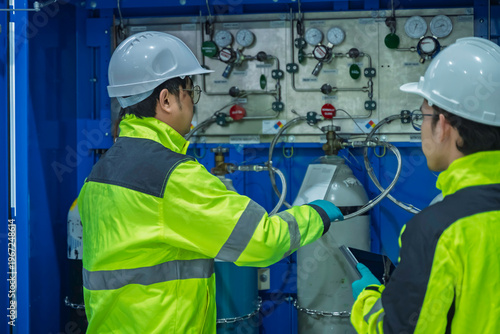 Fotografi Two Asian engineers inspecting industrial gas manifold system