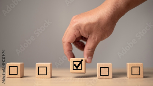 Checklist selection concept with hand choosing approved task block symbolizing efficiency, verification and workflow management. Business quality control, productivity improvement.