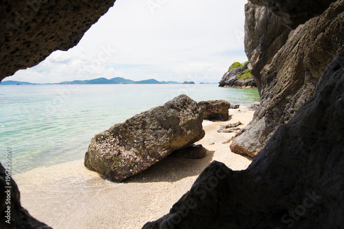 view from the cave to the sea and rock in the sand.