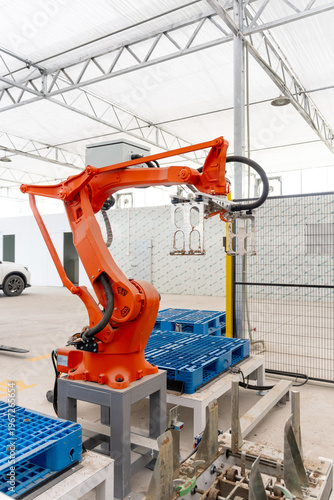 Canvas Print Orange industrial robotic arm operating on blue pallet production line in factor