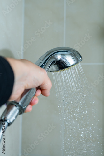 Duschkof in der Hand mit fliessendem Wasser