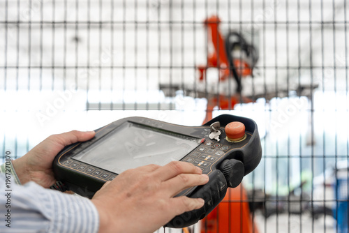 Worker holding an industrial robot teach pendant for operation and control