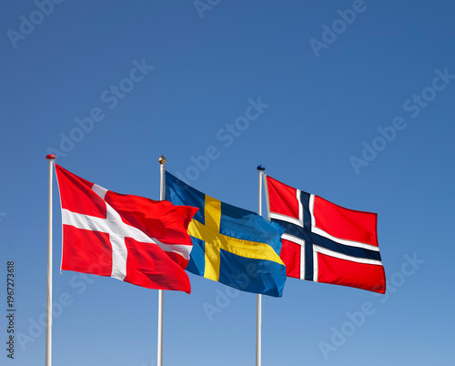 Danish, Swedish and Norwegian national flag waving in the wind against blue sky