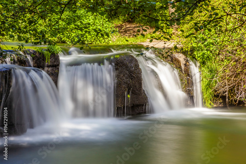 Serene Monte Gelato waterfall amidst vibrant greenery and sunlight
