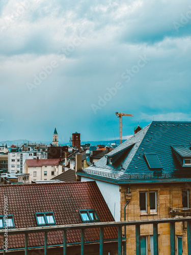Moody European Cityscape with Historic Rooftops, Church Towers  under Dramatic Cloudy Sky