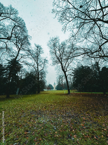 Snowfall Serenity in a Historic European Park with a Baroque Palace Tower Framed by Bare Winter Trees