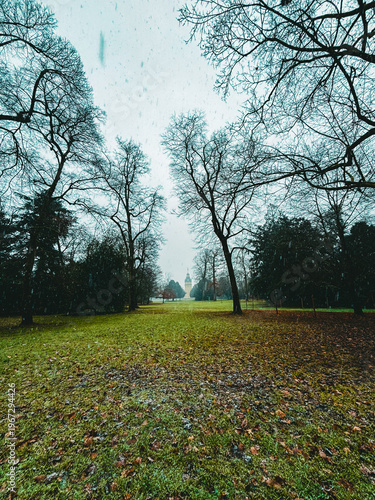 Snowfall Serenity in a Historic European Park with a Baroque Palace Tower Framed by Bare Winter Trees